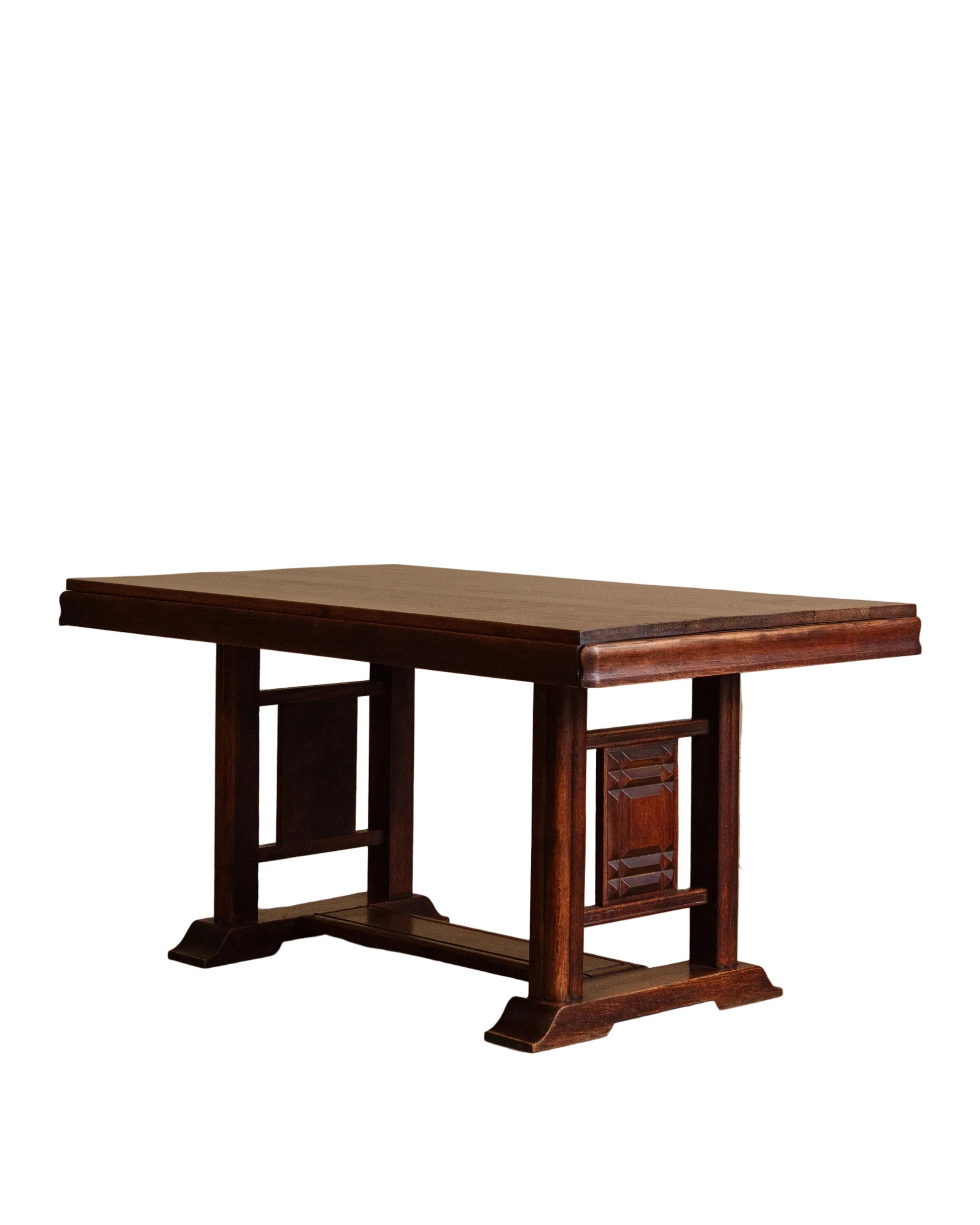 Wooden table with a rustic design on a wooden floor against a beige wall.