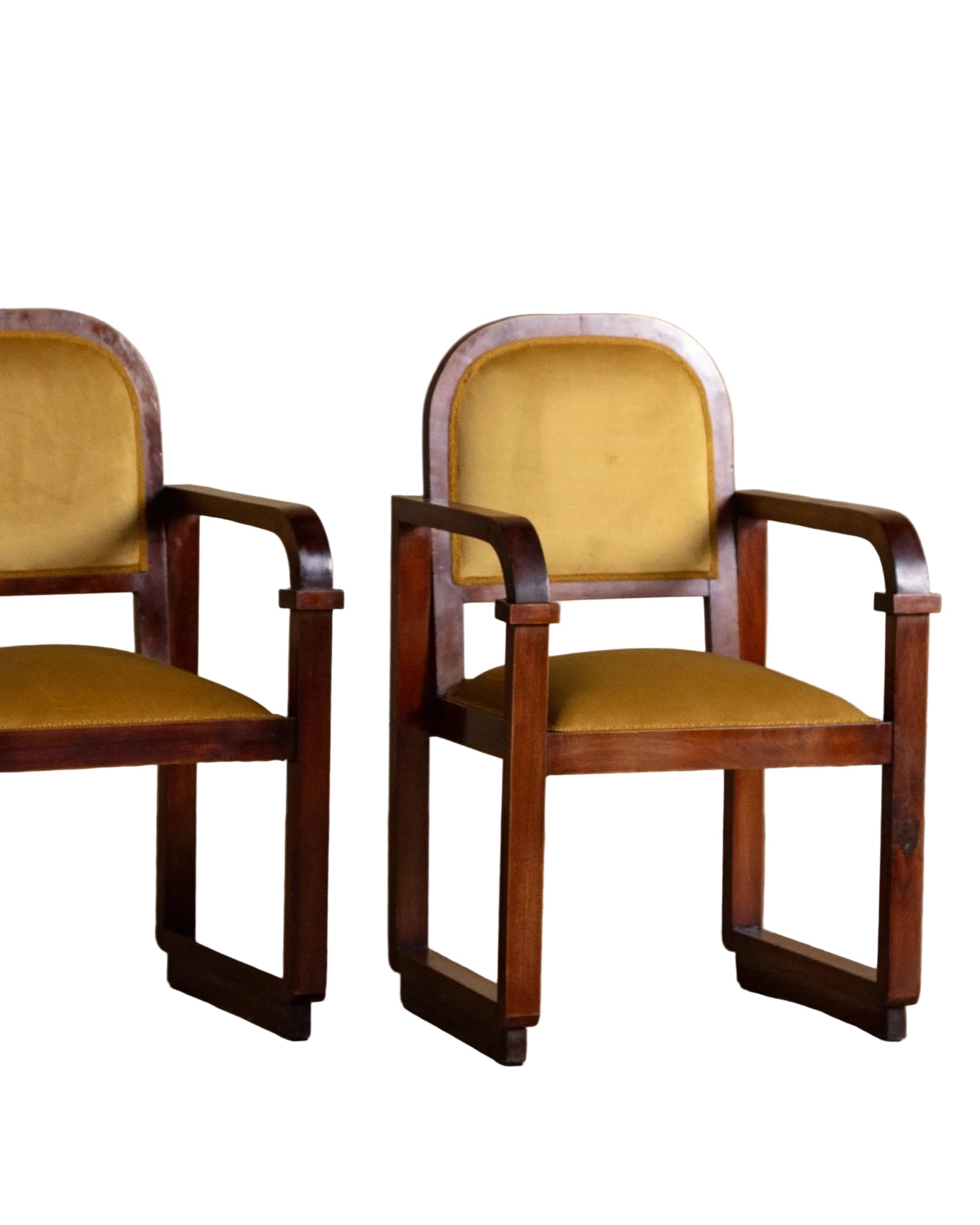 Two wooden chairs with yellow cushions on a wooden floor and beige wall background
