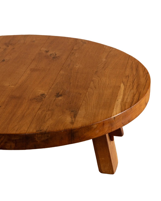 Round wooden table with a natural finish on a wooden floor.
