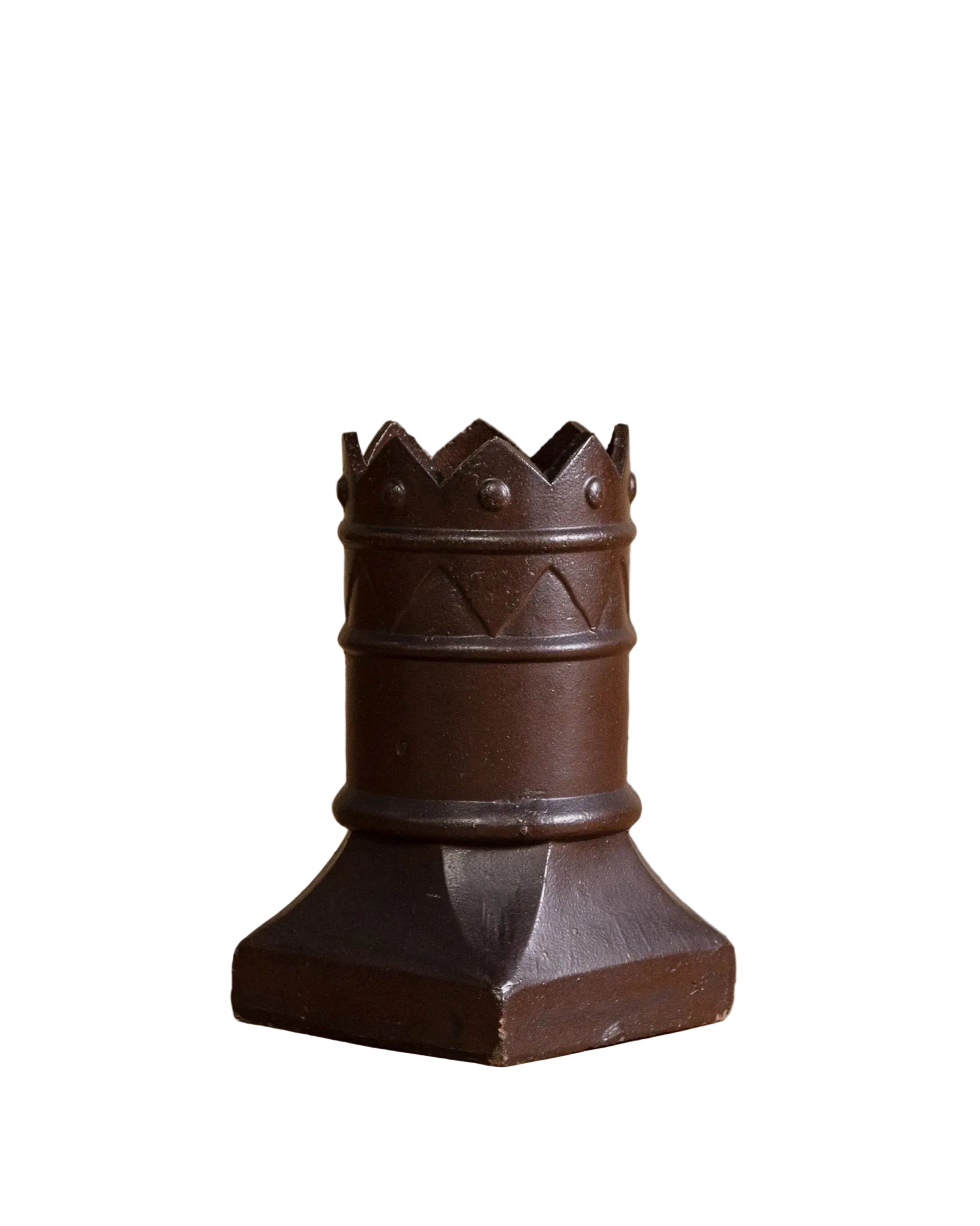 Decorative brown vase with a crown-like top on a wooden surface.