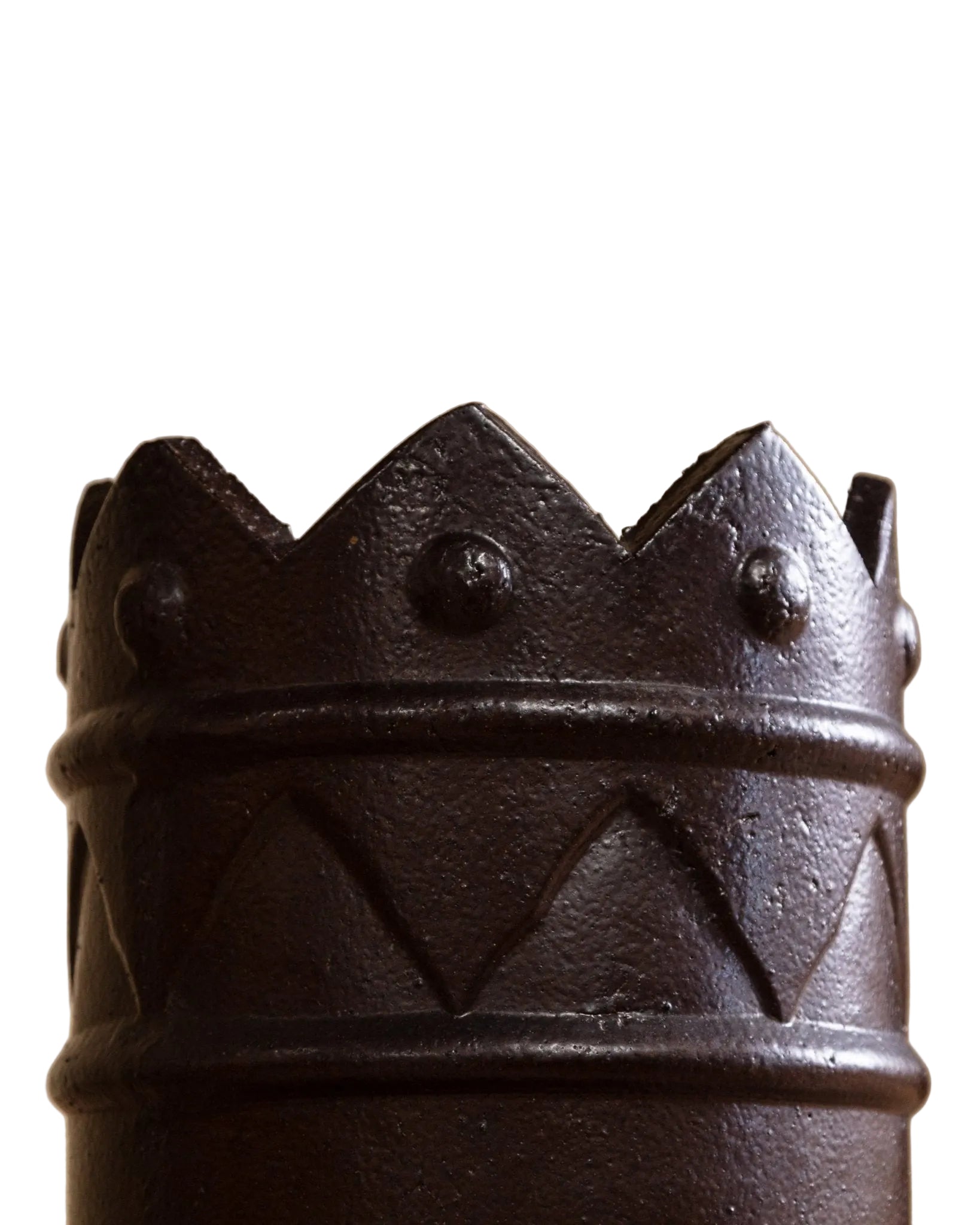 Close-up of a dark brown metal object with intricate design on a beige background