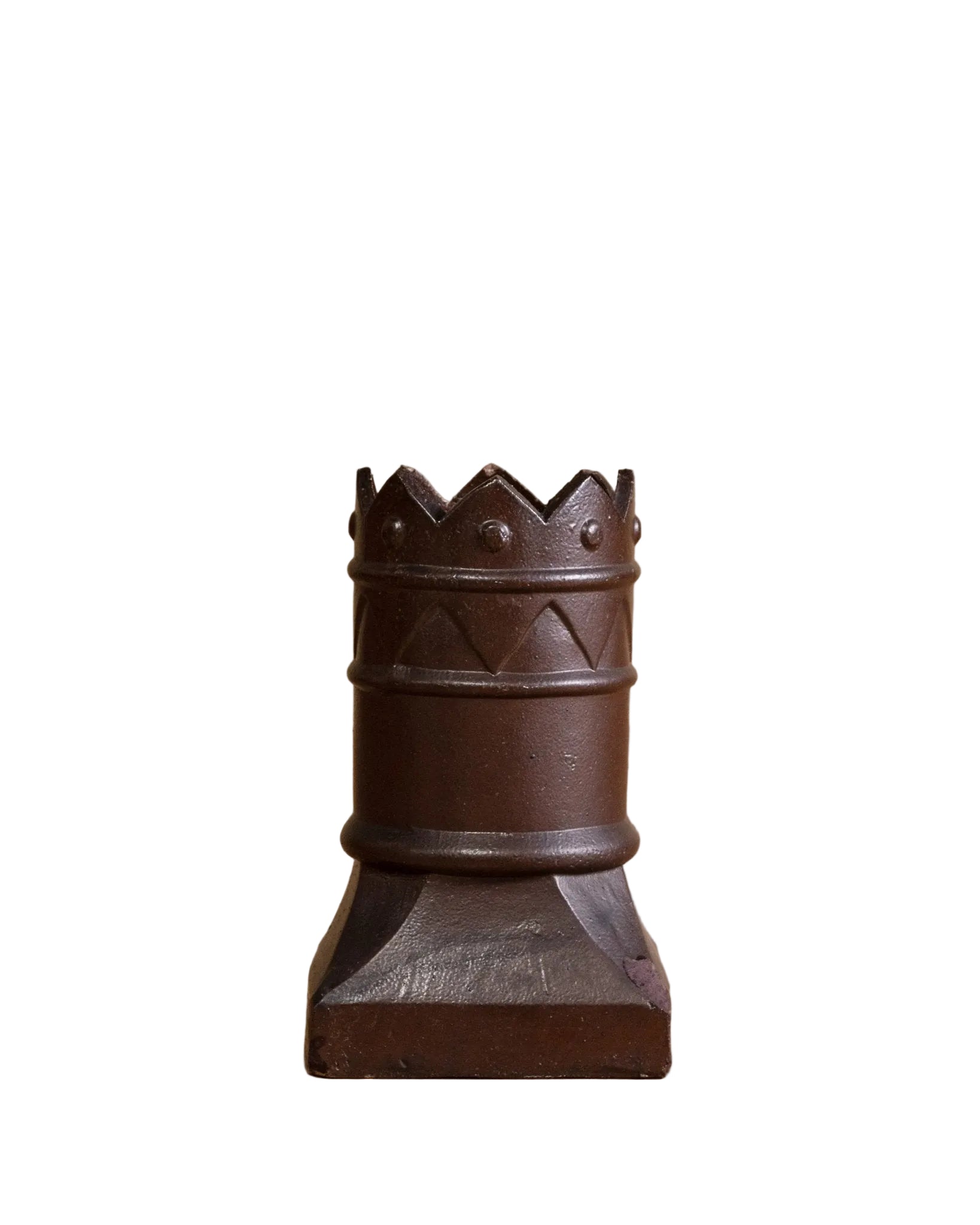 Wooden chess piece resembling a king on a wooden floor with a beige wall background