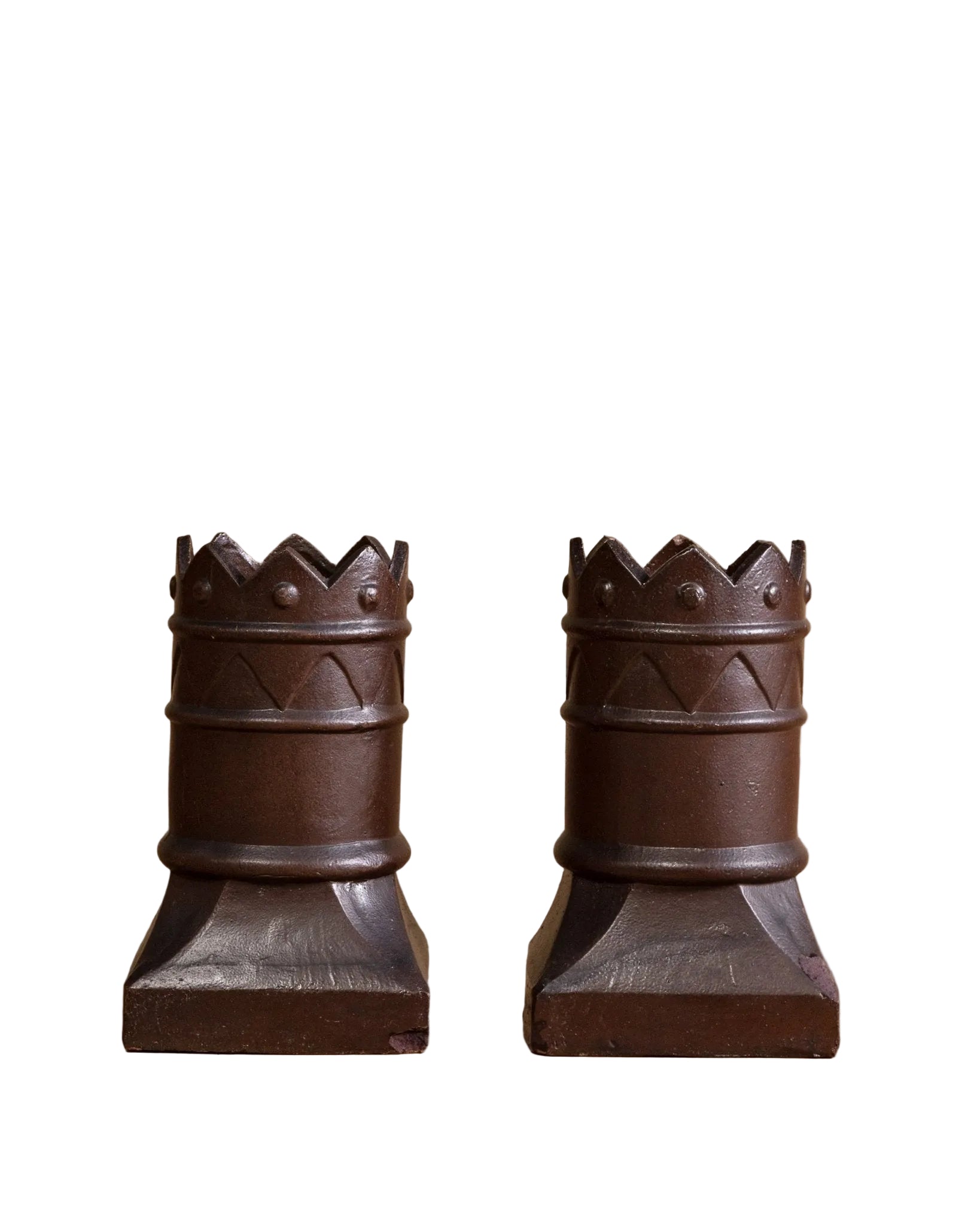 Two ornate wooden candle holders on a wooden surface with a beige background
