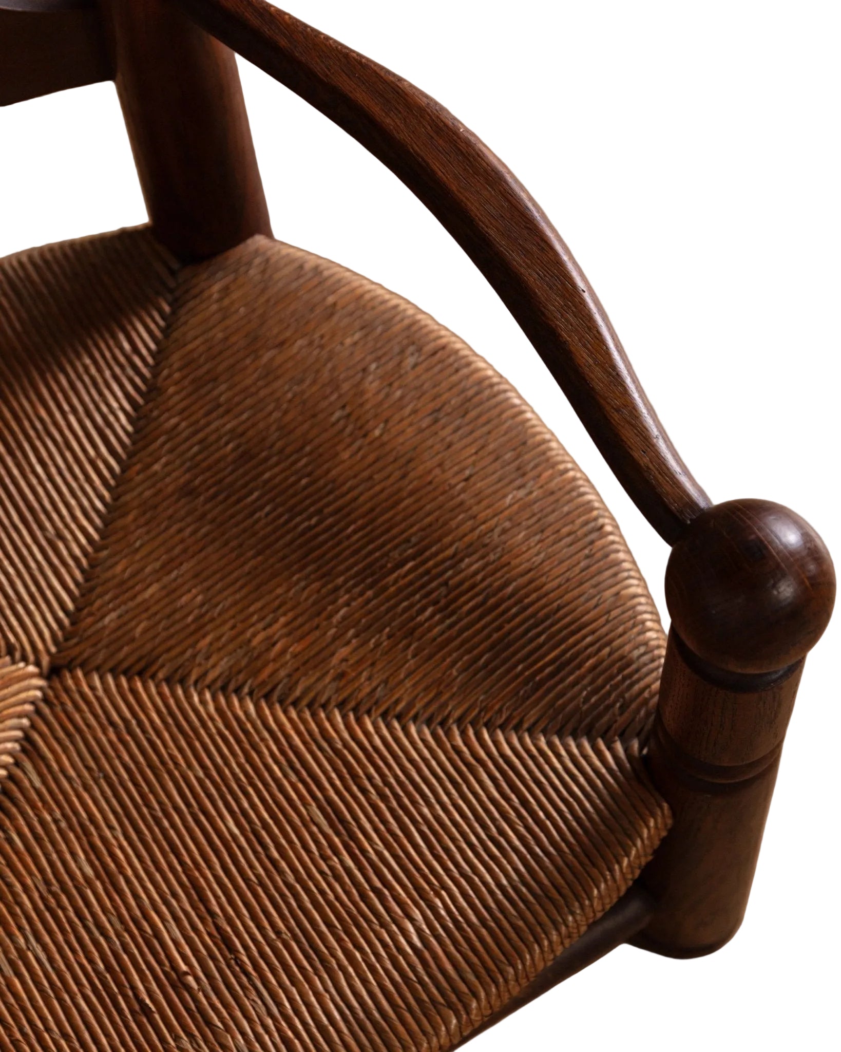 Close-up of a wooden chair with a woven seat on a wooden floor.