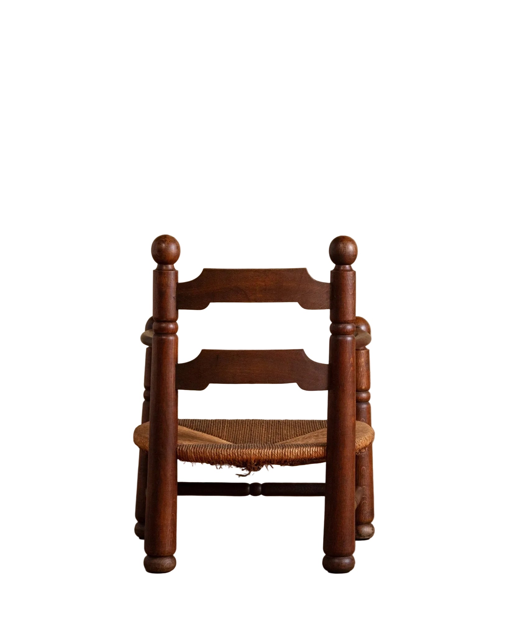 Wooden chair with a woven seat on a wooden floor against a beige wall