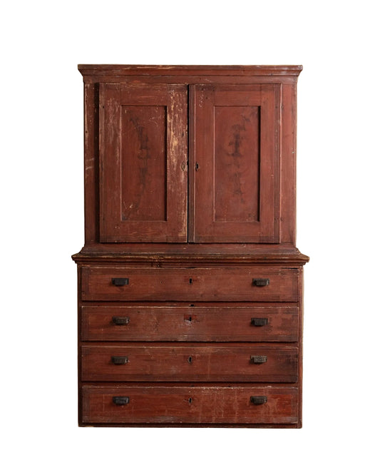 Vintage wooden cabinet with multiple drawers against a beige wall.