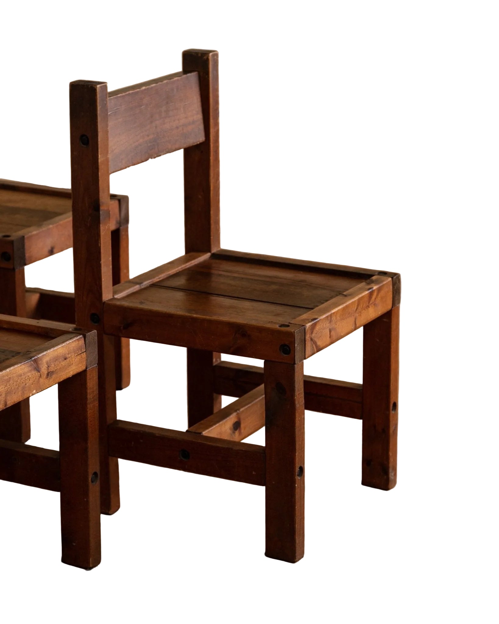 Two wooden chairs on a wooden floor with a neutral background