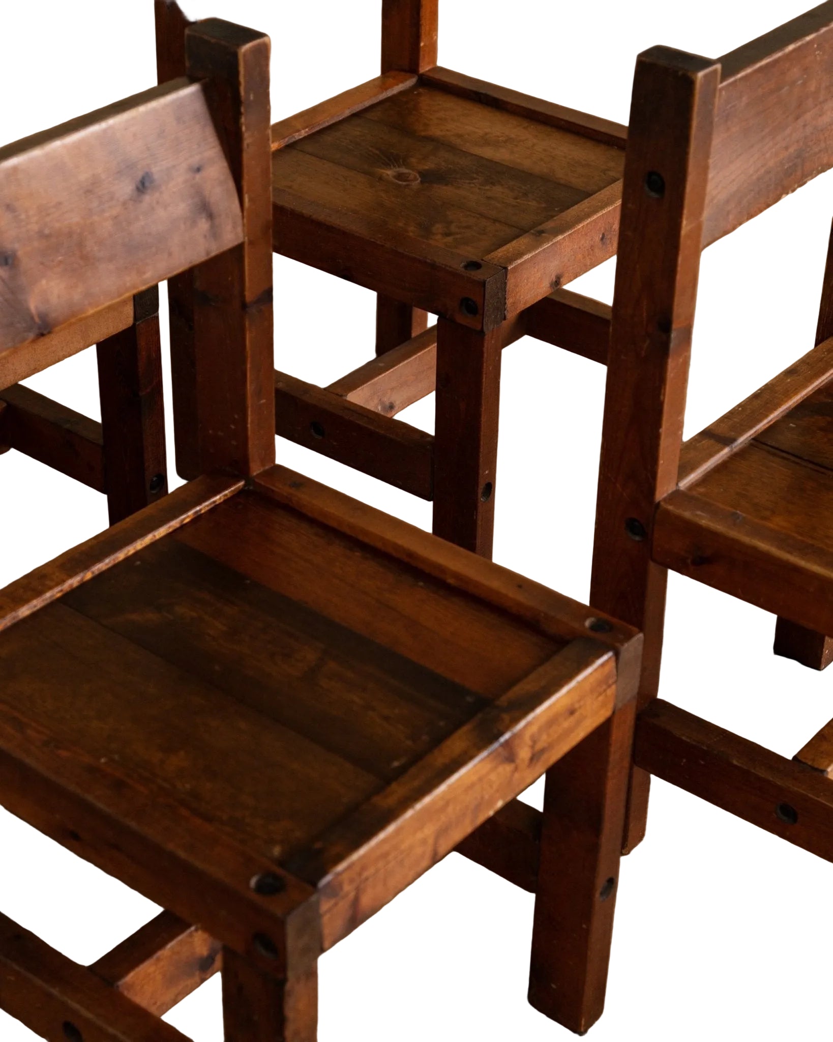 Set of wooden chairs with worn surfaces on a wooden floor.