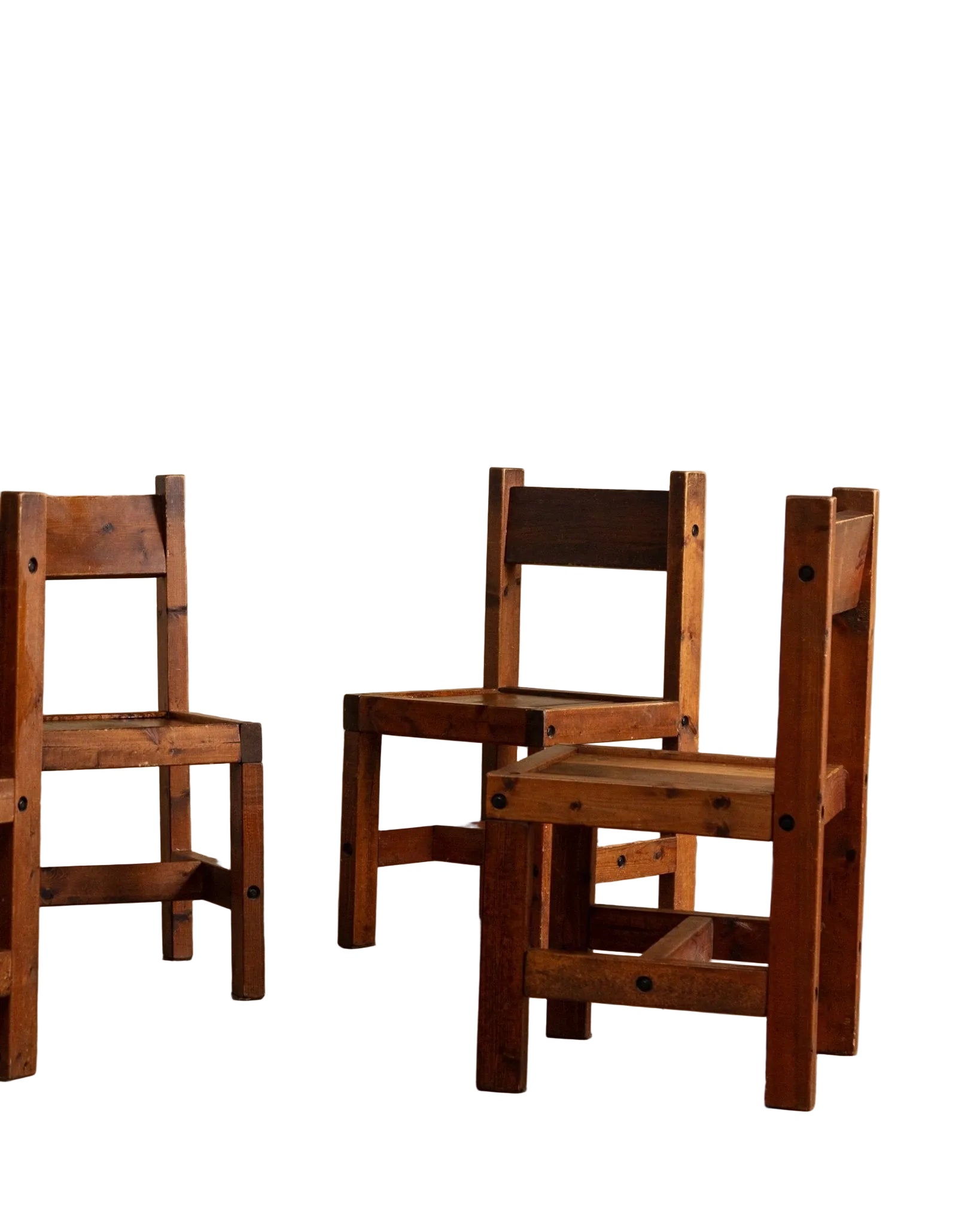 Three wooden chairs against a beige wall