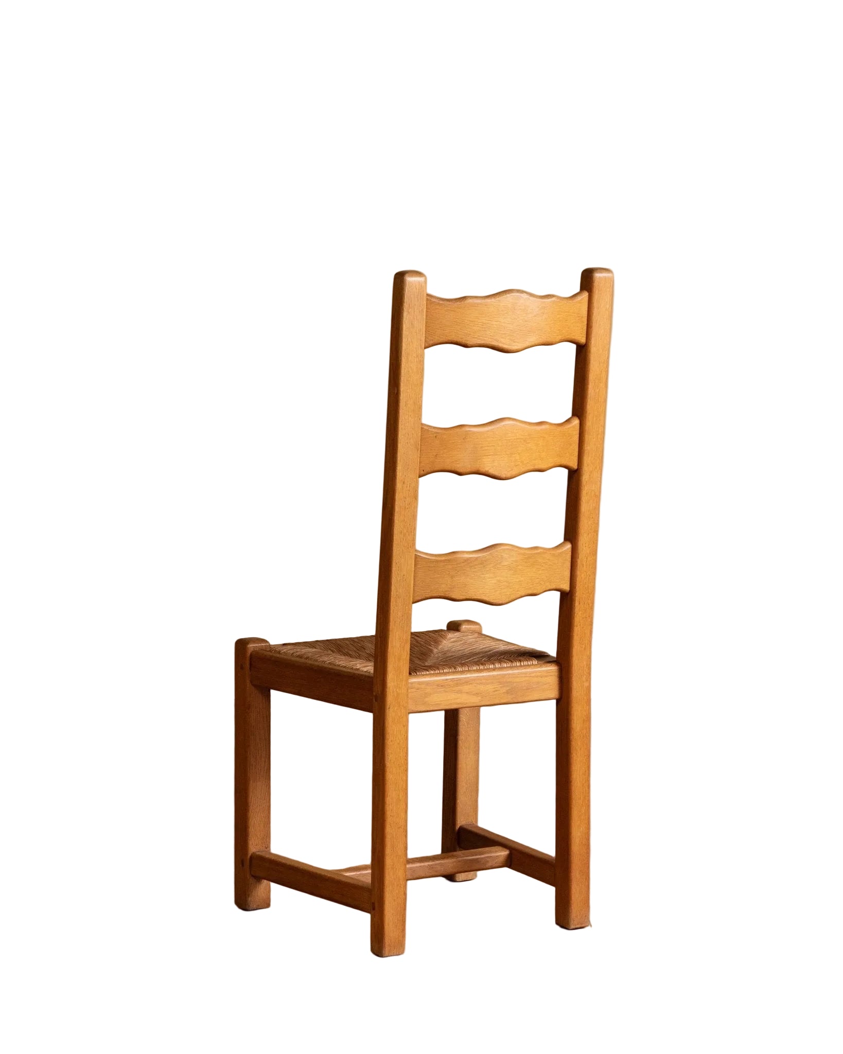 Wooden chair with woven seat on a wooden floor against a beige wall