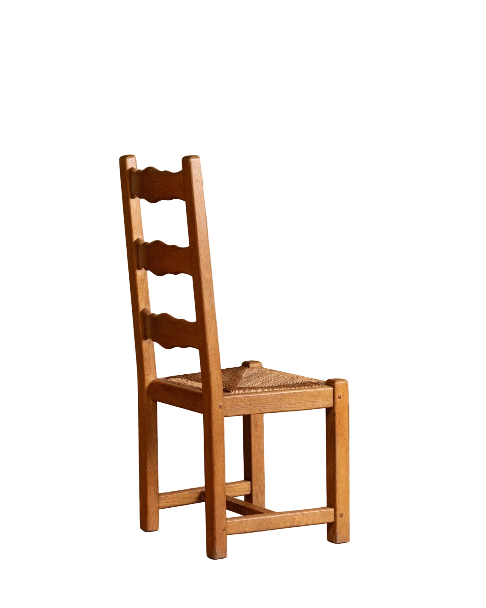 Wooden chair with woven seat on a wooden floor against a beige wall