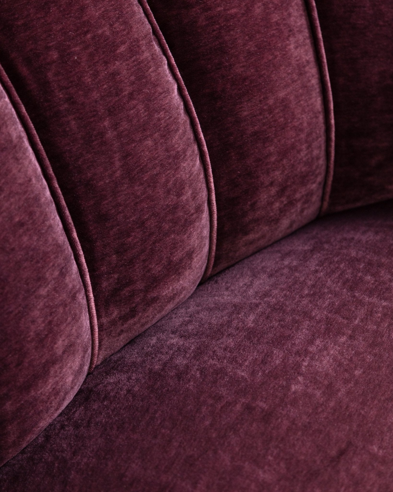 Close-up of a burgundy velvet sofa with a focus on texture and color.