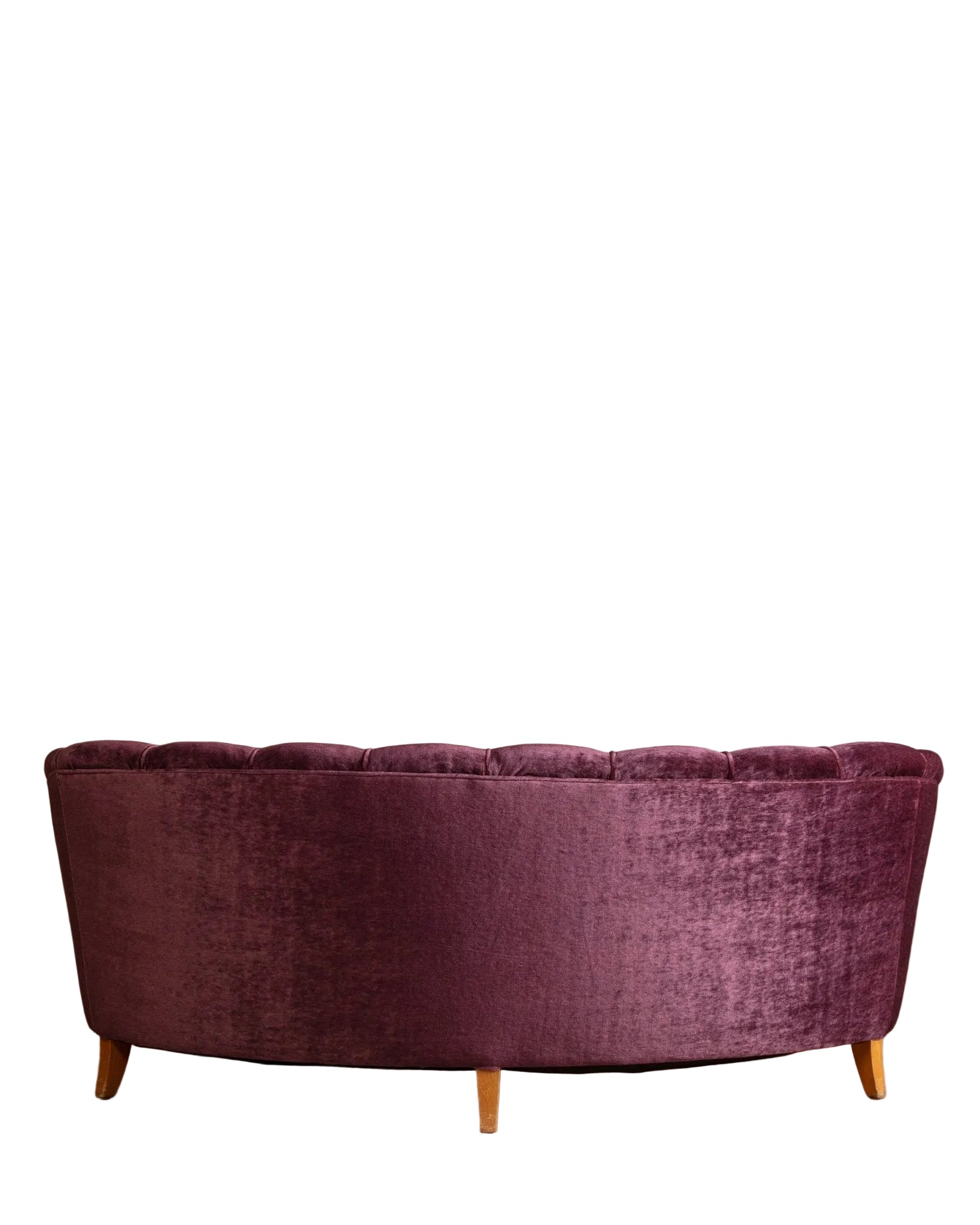 Purple velvet sofa against a beige wall