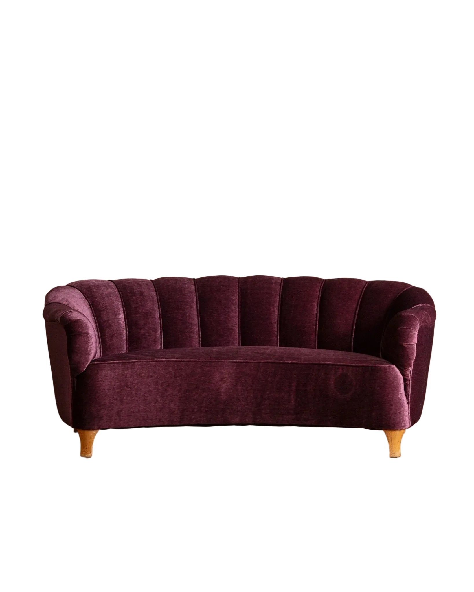 Purple velvet sofa on a wooden floor with a beige wall background
