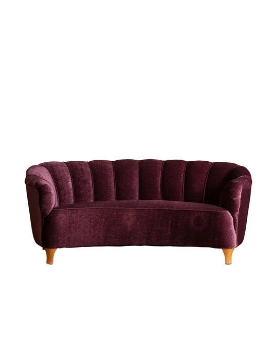 Purple velvet sofa on a wooden floor with a beige wall background