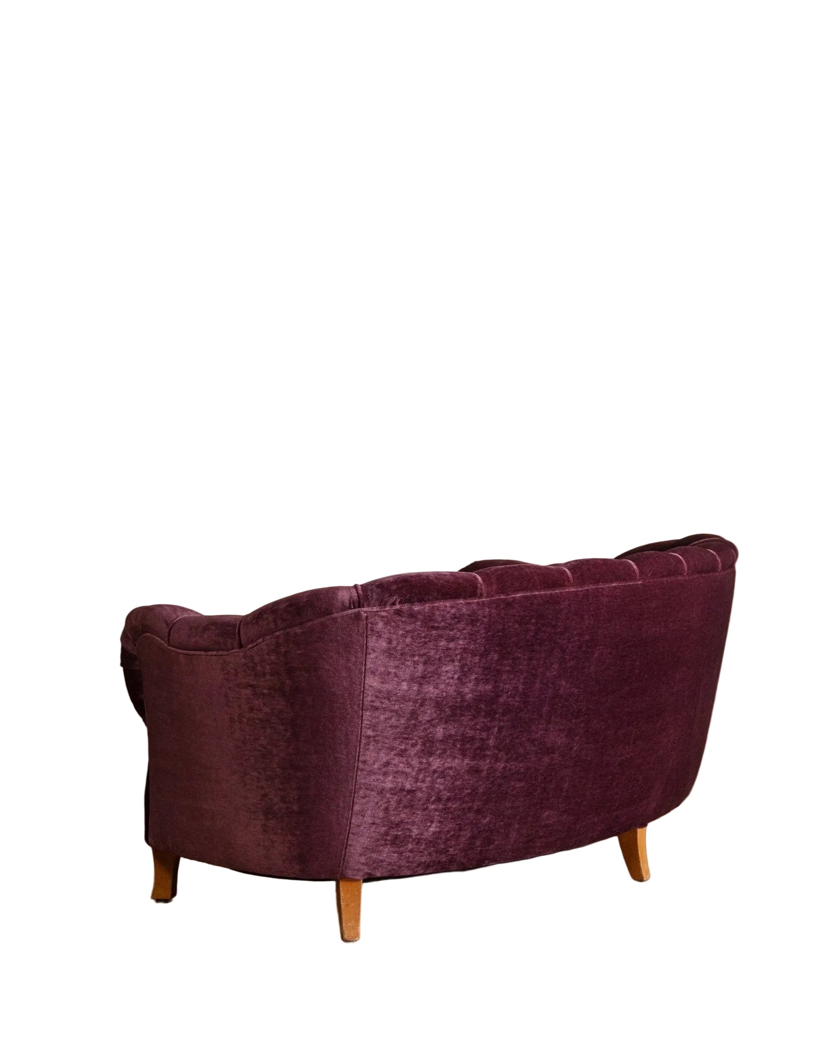 Purple velvet sofa on a wooden floor with a beige wall background